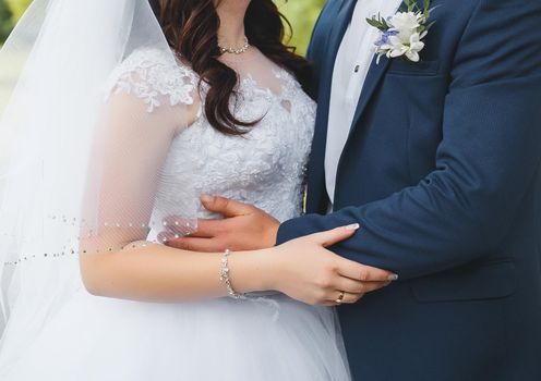 The hands of the bride and groom hug each other. Tenderness and hugs of a man and a woman at a wedding.