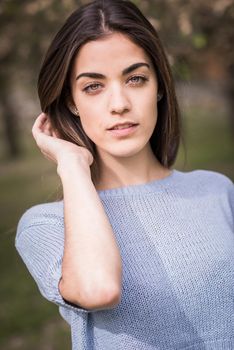 Portrait of young woman in urban park wearing casual clothes. Girl wearing sweater