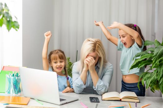 tired mother working at laptop and two little daughters playing