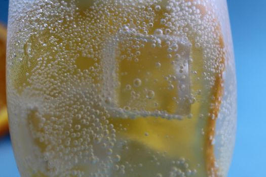 Lemonade water divorcing in a glass of ice and orange is very close-up. Macrophoto.