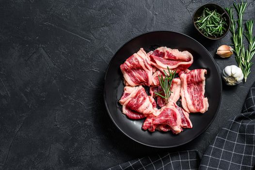 Strips of marbled beef, quick steak. Black background. Top view. Copy space.