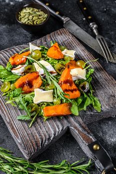 Roasted pumpkin with camembert cheese and herbs. Healthy vegan food concept. Black background. Top view.
