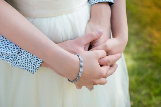 Men's and women's hugs. The guy's hands are held by the girl's arms from behind. Romantic relationships.