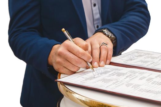Groom's man's hands put on the signature in the magazine about consent to marriage at the wedding.