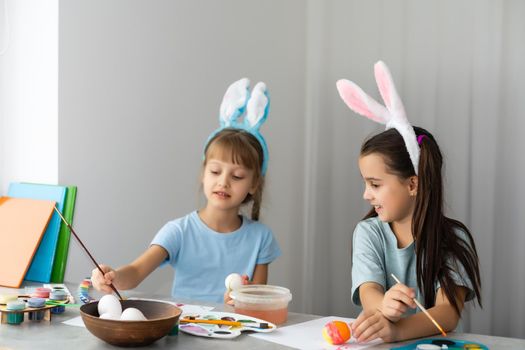Two little cute girls painting on Easter eggs