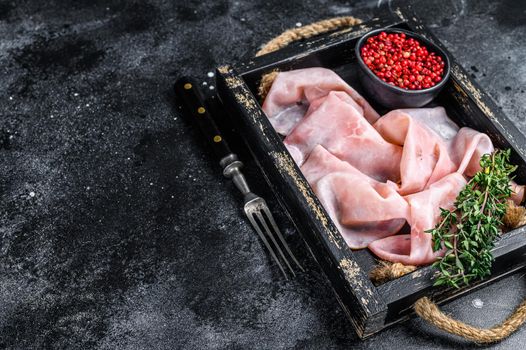 Thin sliced Smoked pork ham in wooden tray. Black background. Top view. Copy space.