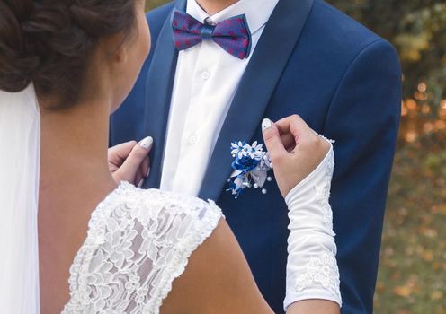The bride and groom's hug at the wedding. A man in a blue suit and white shirt, with a butterfly hugs a girl in a white dress.