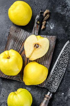 Fresh gold quince fruits on a cutting board. Black background. Top view.