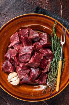 Cut Beef or veal raw heart in a rustic plate with herbs. Dark background. Top View.