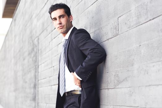 Businessman wearing blue suit and tie in urban background. Man with formal clothes in the street. Blue eyes guy.