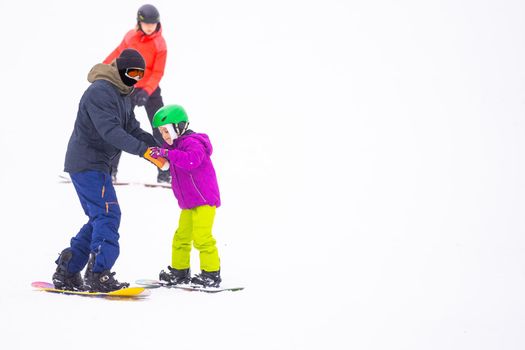 At Cold Winder Day at Mountain Ski Resort Father Teaching Little Daughter Snowboarding