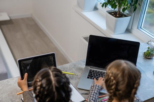 Education at home concept - two Cute little playful girls studying doing homework on laptop