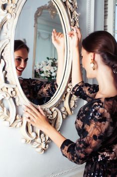 young pretty lady in black lace fashion style dress posing in rich interior of royal hotel room with mirror, luxury lifestyle people concept closeup