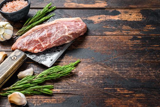 Raw picanha or Top Sirloin Cap steak on a meat cleaver. Dark wooden background. Top view. Copy space.