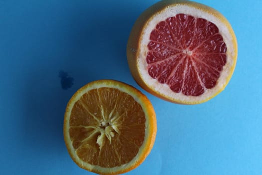 Half of grapefruit and orange on a blue background. View from above Flatley.