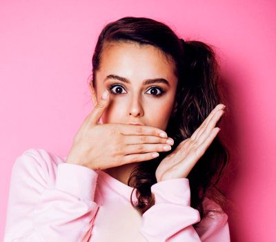 young pretty teenage girl emotional posing on pink background, fashion lifestyle people concept closeup copyspace