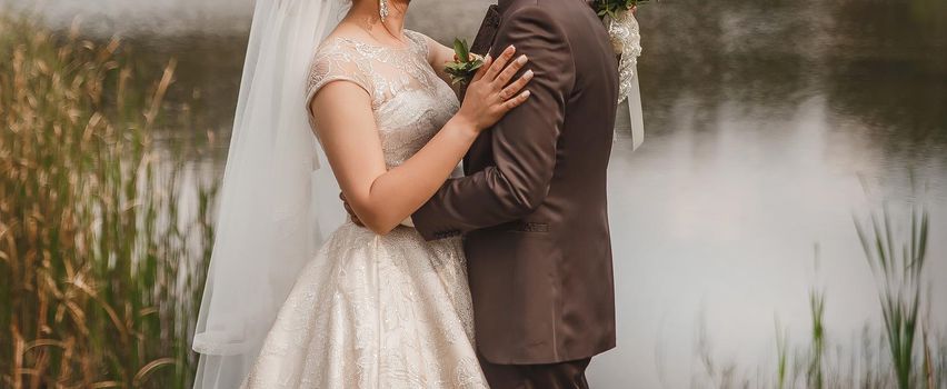 The bride put her hand on the groom's shoulder in a brown suit outdoor.