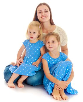 Beautiful young mother with her two daughters. Girls in the same dress with polka dots. Look directly at the camera.The concept of family happiness and mutual understanding between parents