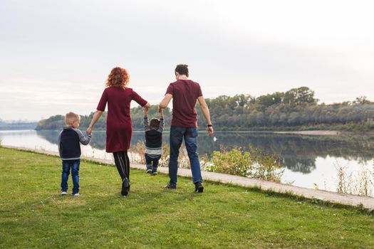 Parent, childhood and nature concept - Family playing with two sons by the water.