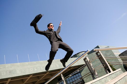 Young handsome businessman jumping in the street