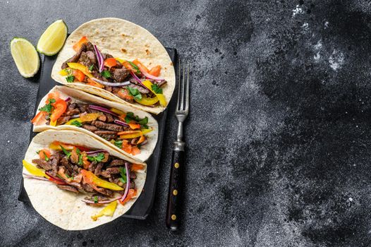 Mexican tacos shells with beef meat, onion, tomato and sweet pepper. Black background. Top view. Copy space.