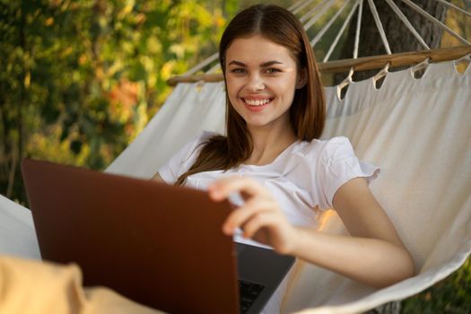 woman with laptop lies in hammock freelance travel. High quality photo