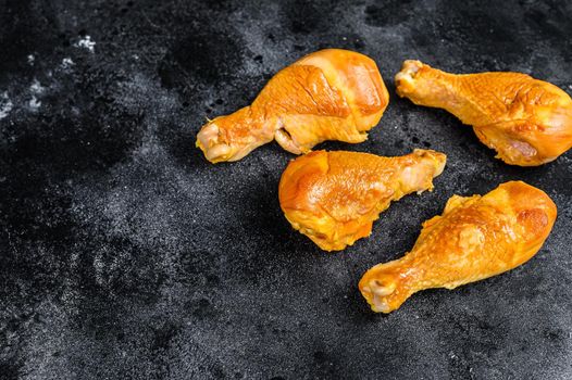 Spicy Smoked chicken leg drumsticks on a kitchen table. Black background. Top view. Copy space.