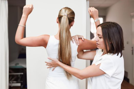 female physiotherapist inspecting her patient. Medical check at the shoulder in a physiotherapy center.