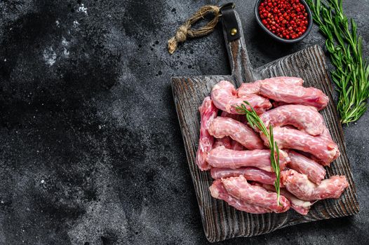 Raw chicken neck meat on a cutting board. Black background. Top view. Copy space.