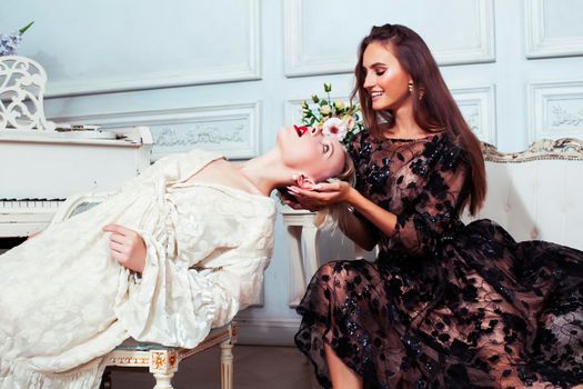 young pretty brunette ballet dancer at piano with blond woman in luxury royal interior, lifestyle rich people concept closeup