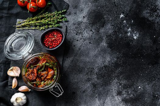 Recipe for cooking dried tomatoes in olive oil with spices and herbs. Black background. Top view. Copy space.