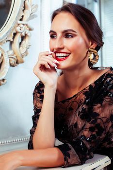 young pretty woman in black lace fashion style dress posing in rich interior of royal hotel room, luxury lifestyle people concept closeup