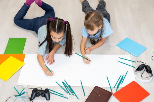 Cute children are painting and smiling while lying on the floor at home