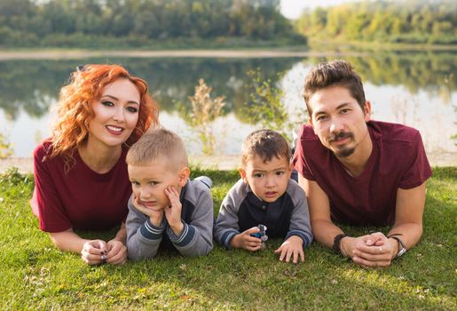 Children, parenthood and nature concept - Big family lying on the grass.