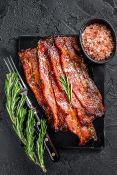 Fried crunchy Streaky Bacon stripes. Black background. Top view.