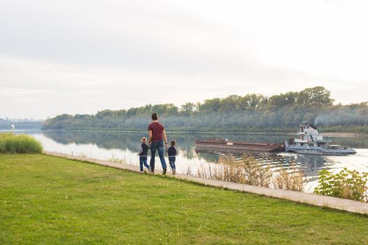 People and nature concept - Father walking with two boys by the water.