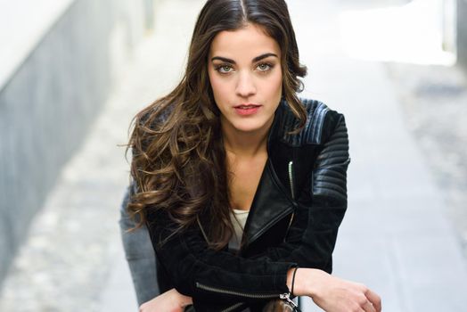 Portrait of young woman in urban background wearing casual clothes looking at camera