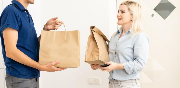 woman receiving boxes from postman at the door in home delivery concept. Woman received the parcel from the postman at home. Postman giving cardboard box to young woman.