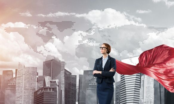 Young confident businesswoman wearing red cape against modern city background
