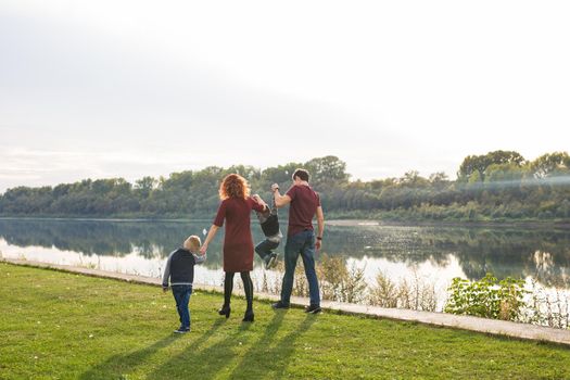 Parent, childhood and nature concept - Family playing with two sons by the water.