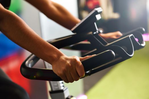 Close-up of woman's hands training at a gym doing spinning or cyclo indoor. Sports and fitness concept.