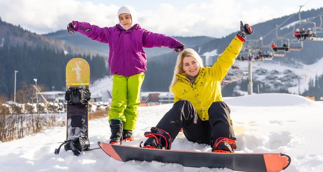 mother and daughter with snowboards in a mountain resort