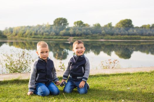 Children and nature concept - Two brothers sitting on the grass over nature background.