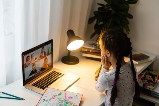 Little girl studying online using her laptop at home