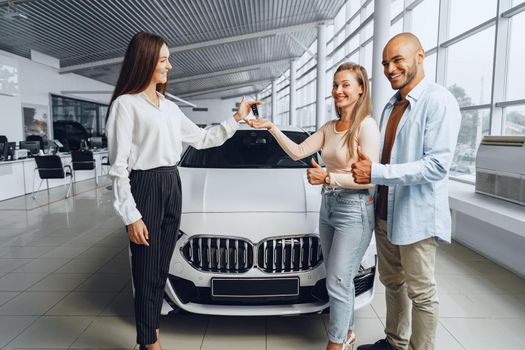 Car saleswoman in a car dealership having a talk with clients buyers