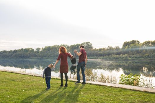 Parenthood and nature concept -Family of mother and father with two boys twins kids in a park at summer by a river at sunny day.