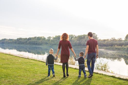 Parent, childhood and nature concept - Family playing with two sons by the water.