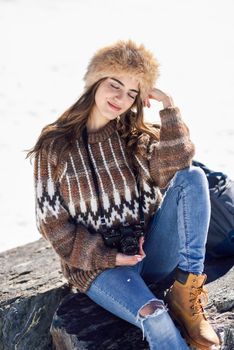 Young woman taking photographs in the snowy mountains in winter, in Sierra Nevada, Granada, Spain. Female wearing winter clothes.