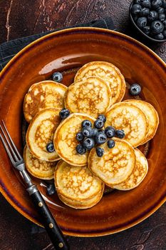Plate with pancakes with fresh blueberries and syrup . Dark background. Top View.