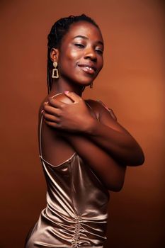 pretty young african american woman with curly hair posing cheerful gesturing on brown background, lifestyle people concept closeup